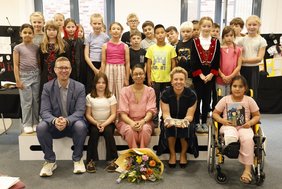 Die Kinder der Klasse 3a zusammen mit NRW-Kulturministerin Ina Brandes, Autorin Ayşe Klinge und Bürgermeister Carsten Hövekamp.