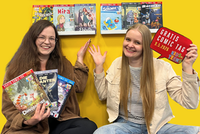Das Foto zeigt die beiden Damen mit zahlreichen Comics.